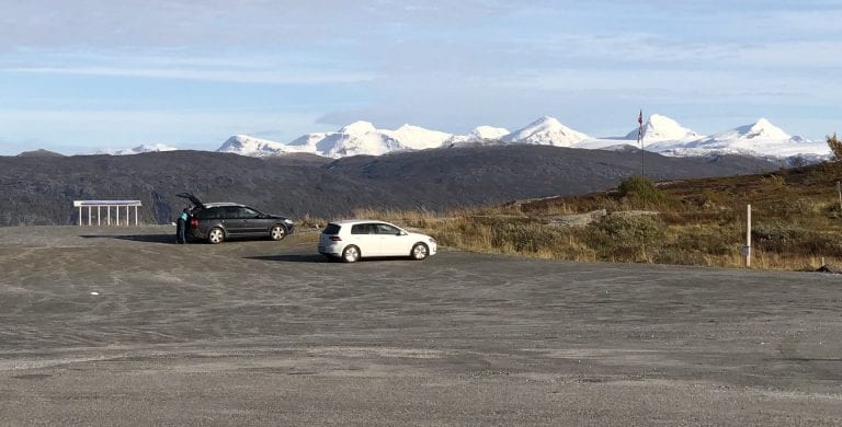 Two cars parked in the parking space at Korgfjellet with a great view of the Okstindan mountains in the horizon.