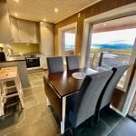Kitchen with dining table in front om panorama windows and mountain view