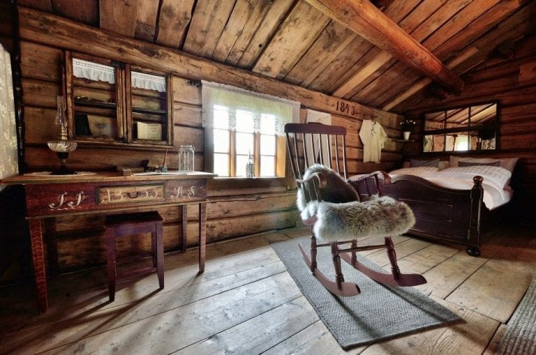 Cozy and old-style bedroom at Inderdalen Farm with a rocking chair, old desk, and bed.