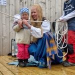 A woman dressed in our national costume helping a child to cut the white thread with scissors at the opening of Rabothytta.