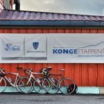 Bikes leaning up against the wall of the red Korgfjellet Fjellstue, underneath an Artic race poster.