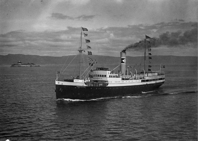 An old black and white photo of the ship DS Nordnorge on the coast.