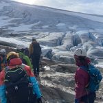 People with helmets getting ready to step onto a glacier