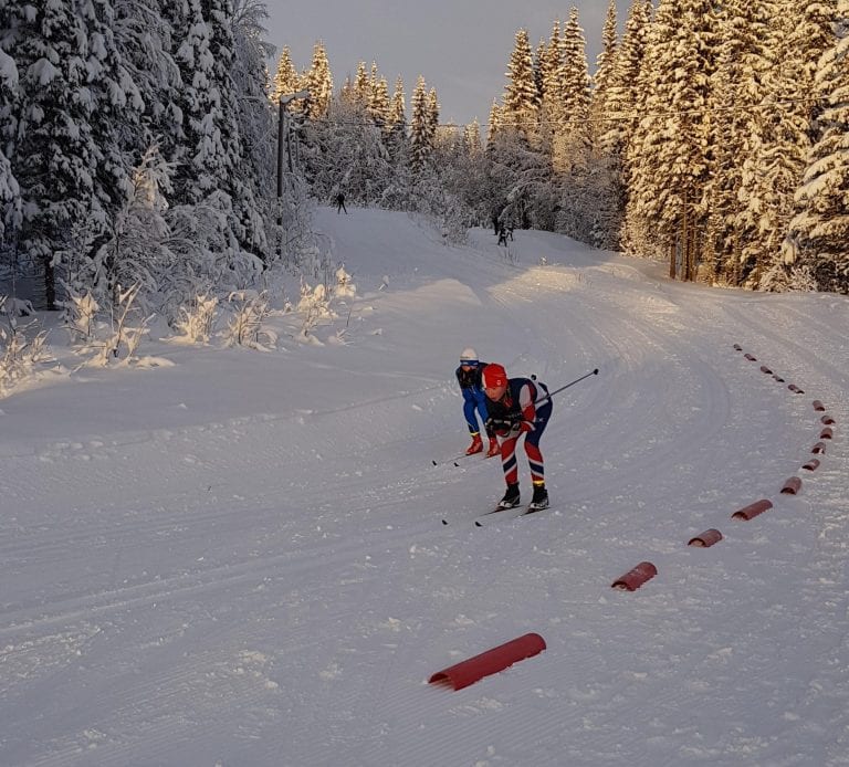 Skiers in tight skiing suits on their way down a small hill during a competition in the skiing trails in Korgen.