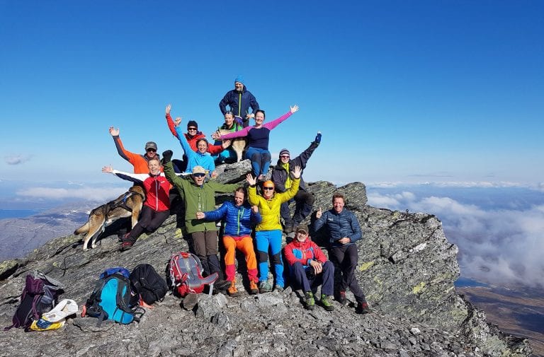 Lots of colorful and happy people celebrating being on top of Oksskolten, Norther-Norway’s highest mountain.
