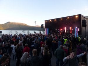 People dancing in front of the stage at "Båt of fjord" festival, located right next to fjord and mountains at Hemnesberget.