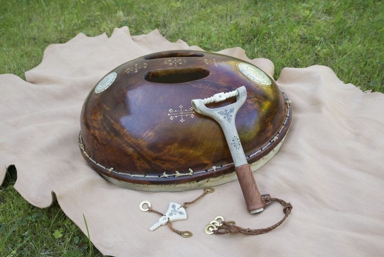 Sami drum with hammer made in shining wood with sami pictograms on it.