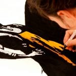 A child drawing a mysterious man dressed in black and orange.