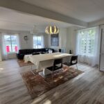 Cozy white apartment with three windows and a big table in front.