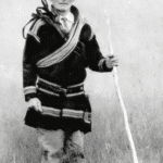 Black and white photo of a man in a robe with a stick.