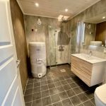 Big bathroom with toilet, shower, sink and mirror.