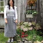Ann Synnøve, dressed in an old costume, standing welcoming in front of her café-entrance at Inderdalen Farm.