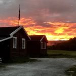 Burning sunrise seen in the horizon over some of the cabins at Korgen Camping.