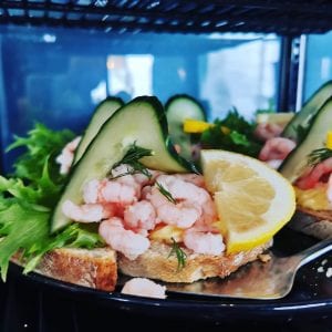 Delicious-looking shrimp sandwich decorated with cucumber, lettuce and lemons at Lille Havfruen Kafé.