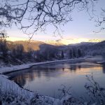 Røssåga river passing Korgen Camping in a purple light during the winter with the sun shining only in the horizon.