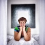 Host and artist, Yvonne, laying on one of the majestic beds with her art on the wall.