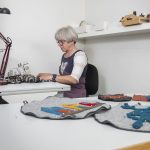 Anne-Lise, the owner of Kråkeslottet, in the process of sowing a new product in her workshop.
