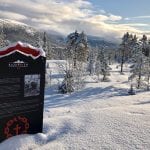An info-sign about “Blodveien” standing outside in a snowy landscape with trees and mountain in the background.