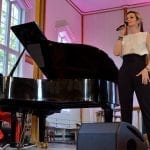Singer next to pianist playing a black grand piano, at a concert inside the church during the jazz festival, Hemnesjazz.