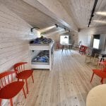 The biggest dormitory located on the loft at Rabothytta in a wooden style with bunkbeds and red chairs.