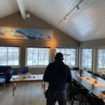 A wooden livingroom with lots of windows towards nature