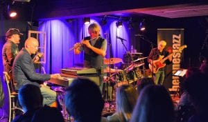 Concert at Jernvaren during the jazz festival at Hemnesberget, with the stage lit up in blue colors behind the five musicians.