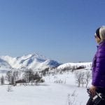 Colorful woman in the mountain looking out on her view of the beautiful, snowy, white mountain, Lukttind.