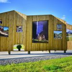 Information board in Korgen made of shining woodwork in the shape of mountains, seen from behind with local pictures.