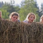 Young, surprised and scared girls sticking their heads up above the wall of straws during the local play, Klemetspelet.