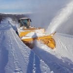 Yellow snowblower preparing the road to the top of Korgfjellet, creating 2-meter-tall walls on the side of the road.