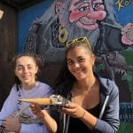 Two smiling girls with an ice cream, sitting in front of a painting of a happy Norwegian troll at Korgfjellet Fjellstue.