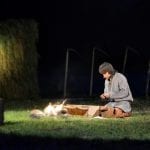 The sami, Klemet, sitting next to an open fire in the outdoor play, Klemetspelet, in Korgen.