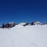 Skiers in an open and white mountain landscape admiring the surrounding mountains.