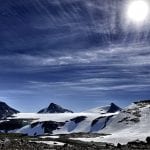 The shining and majestic white Okstind glacier on a sunny day with a clear blue sky.