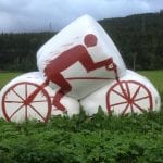 White silage bales standing on an acre, painted with a red cyclist as decoration for “Artic Race” in 2016.