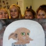 Creative kids posing with a painting of a strange, but cute little creature, they have painted.