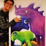 The artist, Yvonne standing next to one of her paintings. This one of colorful and cute imaginary creatures.