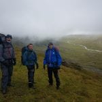 Three hikers on their way down from the cabin, Rabothytta, on a very foggy and cloudy day.