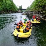 Two yellow rafting boats on the river filled with lots of excited and happy people.