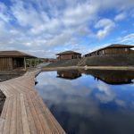 Outdoor pool and sauna in front of wooden cabins.