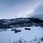 Winter landscape with parked cars and snowmobiles