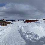 Wooden restaurant and cabins in snow covered mountain landscape.