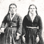 A black and white photo of two girls in dresses.